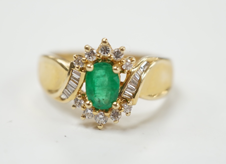 A modern 14k, emerald and diamond cluster set ring, with baguette cut diamond set shoulders, size Q, gross weight 4.9 grams. Condition - fair